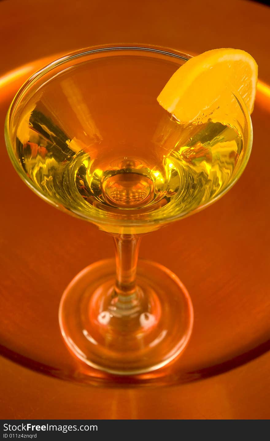 Closeup of a yellow cocktail with a slice of orange on a bronze tray. Closeup of a yellow cocktail with a slice of orange on a bronze tray