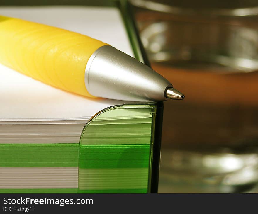 Yellow pen, stack of note pads and glass of water