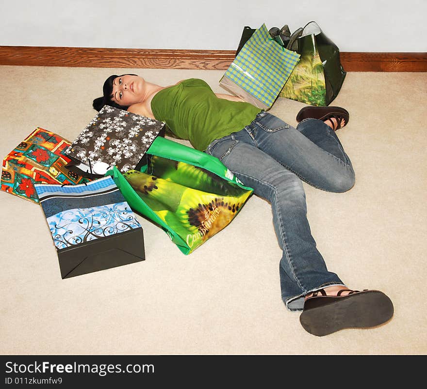 Young woman is back from shopping and totally exhausted, lying on the floor in the living room. Young woman is back from shopping and totally exhausted, lying on the floor in the living room.