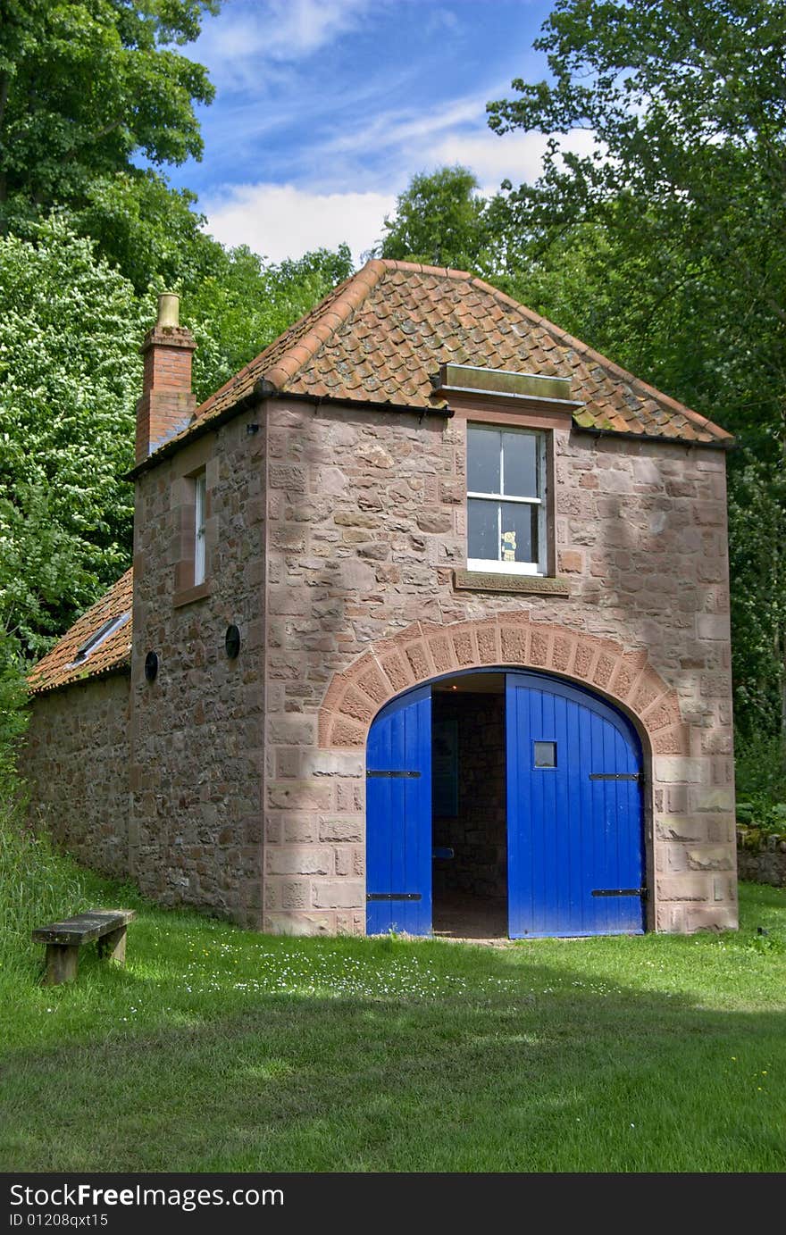 A boathouse with bright blue doors on the river Tweed on the Scottish English border. A boathouse with bright blue doors on the river Tweed on the Scottish English border