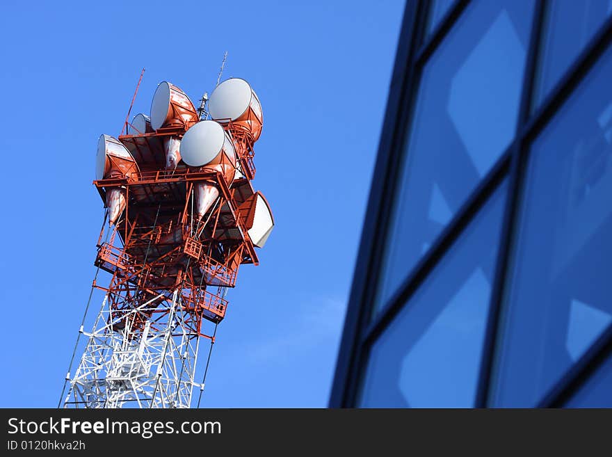 Broadcasting tower against blue sky and building. Broadcasting tower against blue sky and building