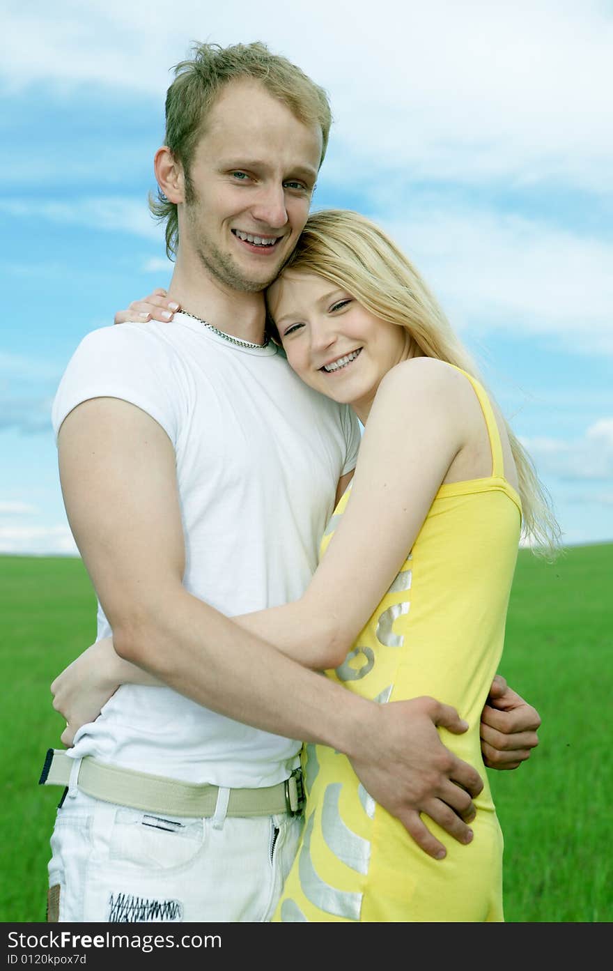 Man and woman in green field under blue sky