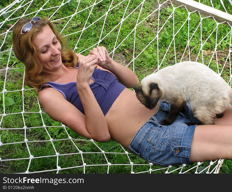 Smiling young woman lying in hammock with cat. Smiling young woman lying in hammock with cat