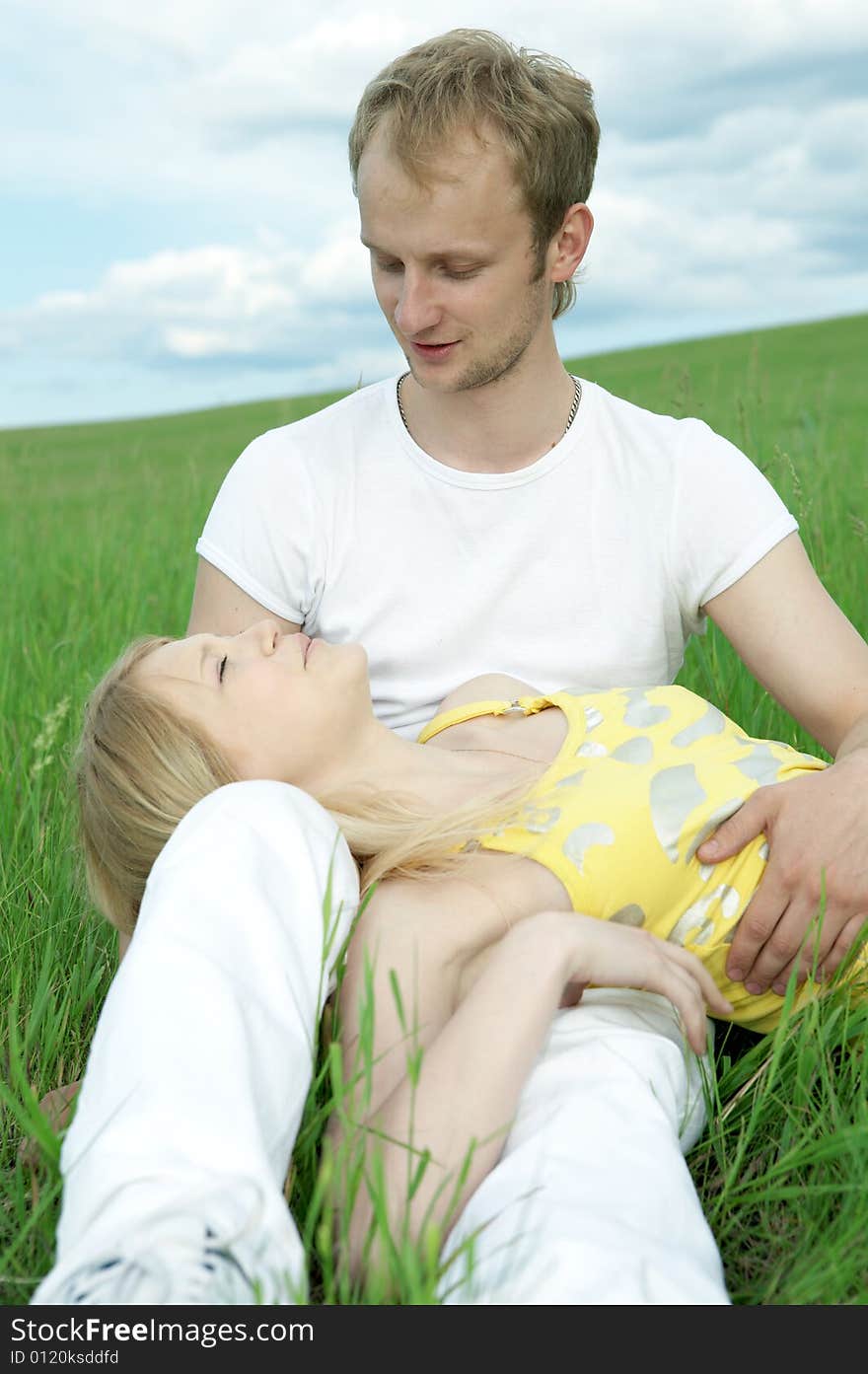 Man and woman in green field under blue sky