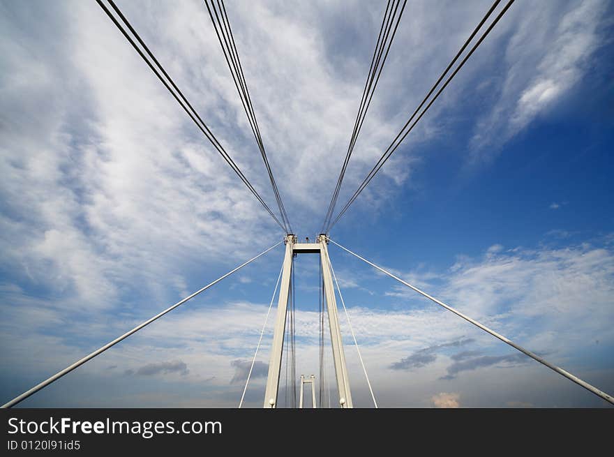 Cable of bridge over blue sky and clouds