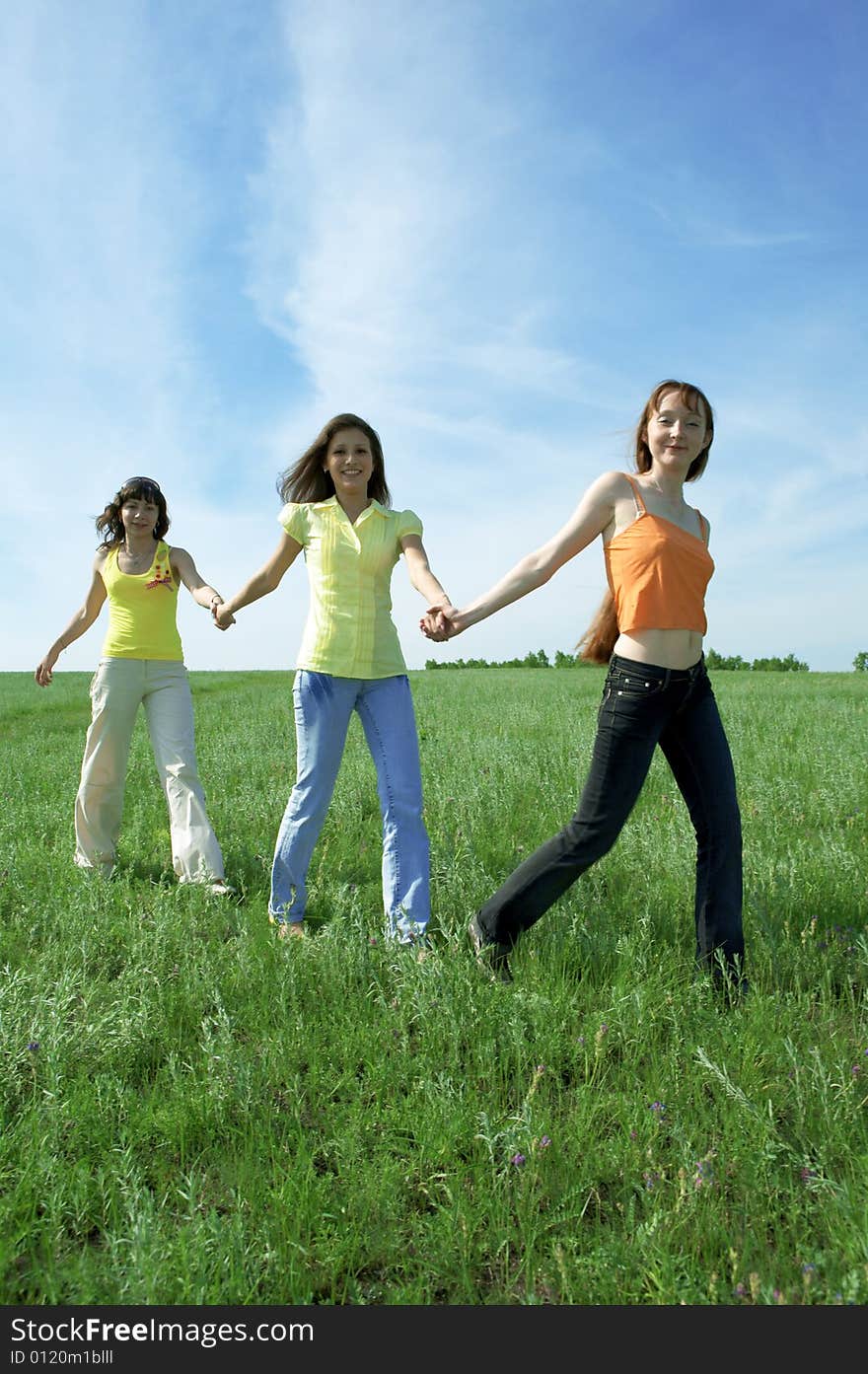 Three girlfriend in green field under blue sky