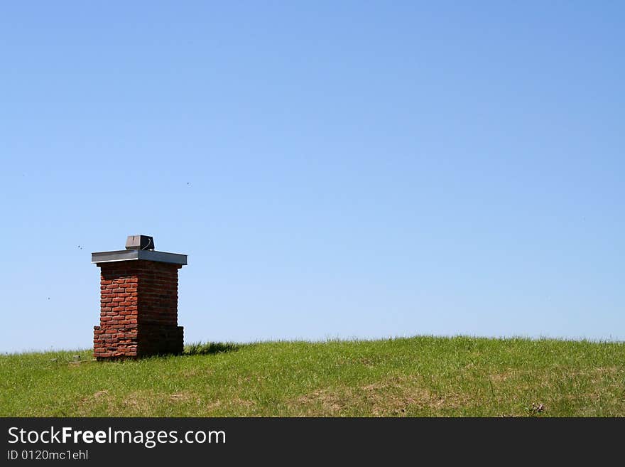 A chimney on a grass roof with a clear blue sky