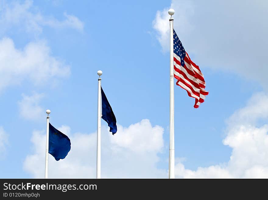 United States flag and two blue flags in a breeze against a scattered cloud sky. United States flag and two blue flags in a breeze against a scattered cloud sky