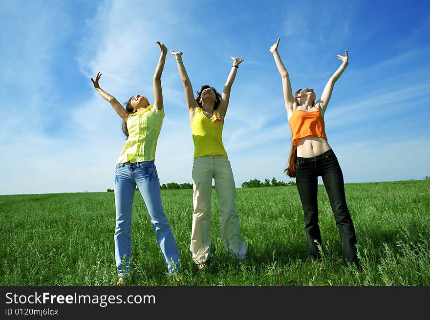 Three girlfriend in green field under blue sky