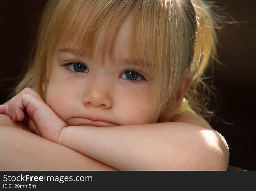 Little girl with pouty/pursed lips resting chin on crossed arms