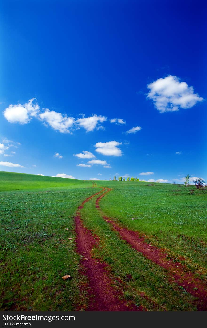 Nature background green field road and blue sky with clouds