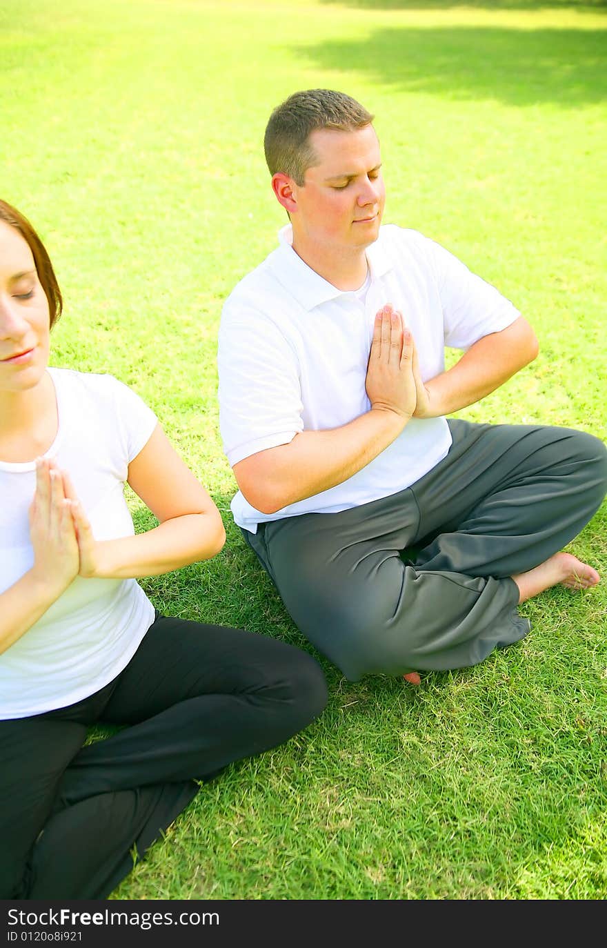 Young caucasian couple meditate outdoor in a park. concept for yoga, family activity or wellbeing. Young caucasian couple meditate outdoor in a park. concept for yoga, family activity or wellbeing