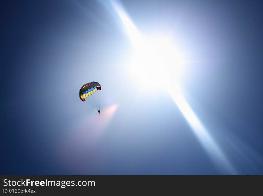 Parachutist at blue sky and bright sun rays