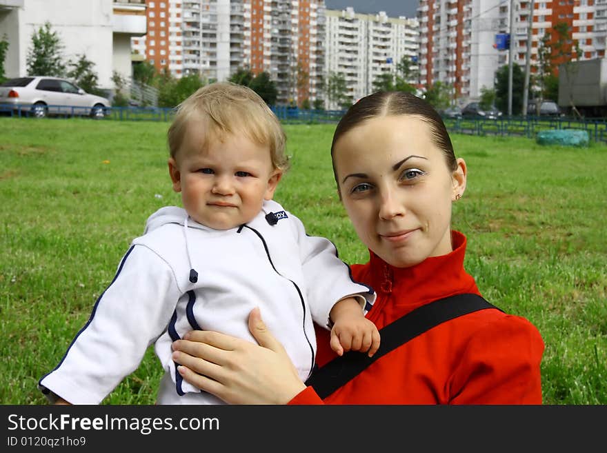 A beautiful girl in a red jacket with a child in her arms. A beautiful girl in a red jacket with a child in her arms