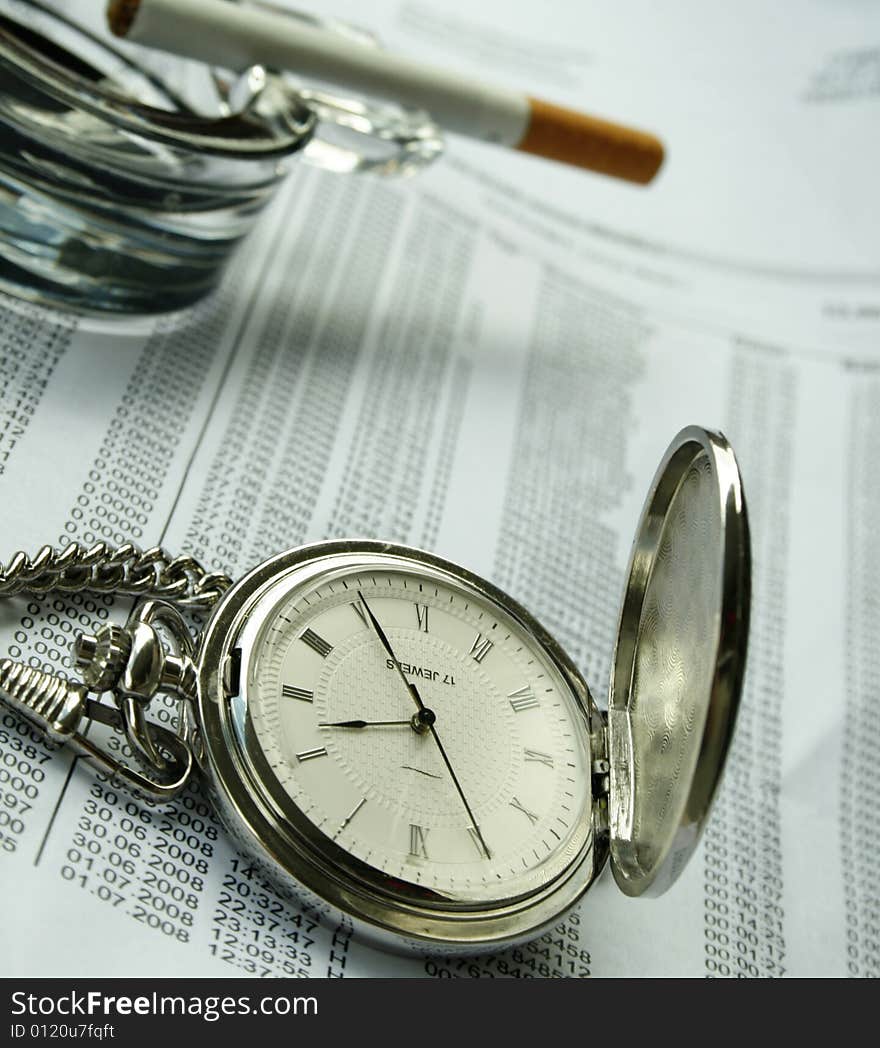 Watch and ashtray with a cigarette on documents