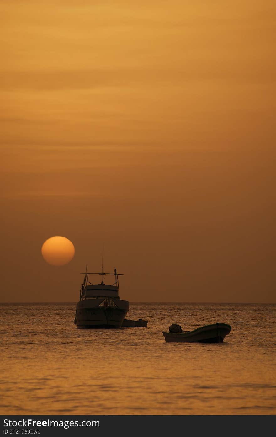 Two boats in front of a setting sun at dusk. Two boats in front of a setting sun at dusk