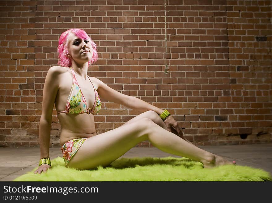 Pretty Woman in a Bikini with Pink Hair on Green Rug. Pretty Woman in a Bikini with Pink Hair on Green Rug