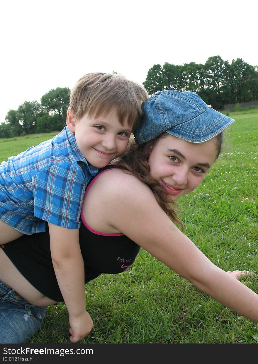 A smiling brother and the sister sit on a grass