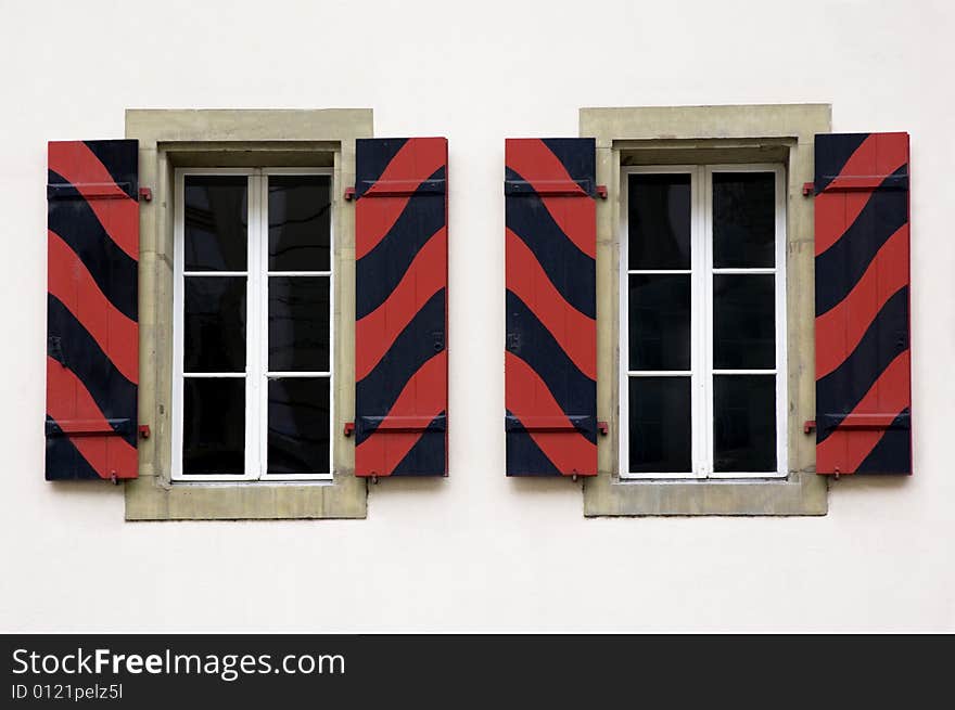 Two windows with blinds painted wavy in red and black. Two windows with blinds painted wavy in red and black