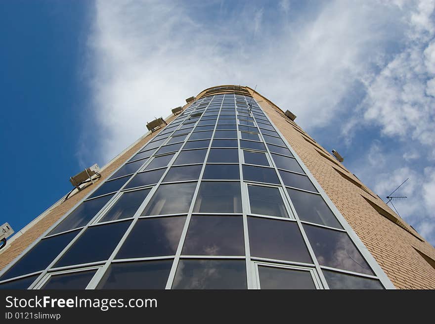 Multistory house of glass and red and yellow bricks in blue sky. Multistory house of glass and red and yellow bricks in blue sky