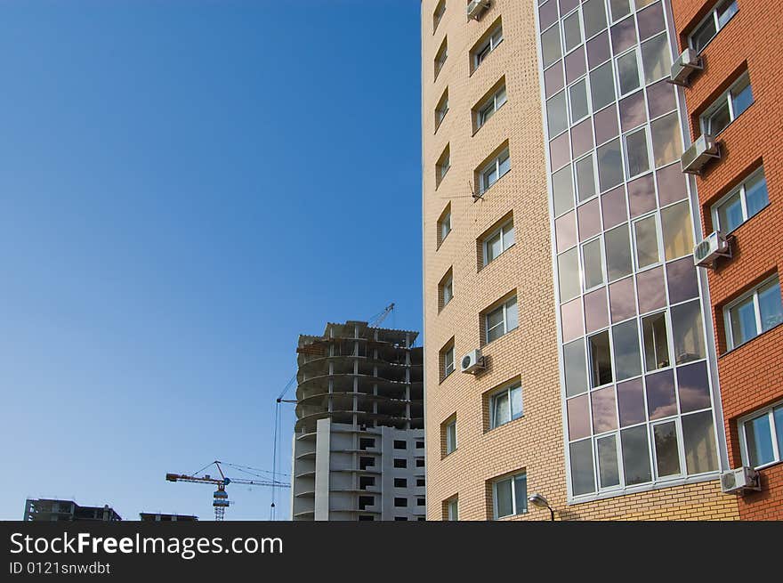 New brick multistory house in the foreground, construction works and tower crane in the background. New brick multistory house in the foreground, construction works and tower crane in the background