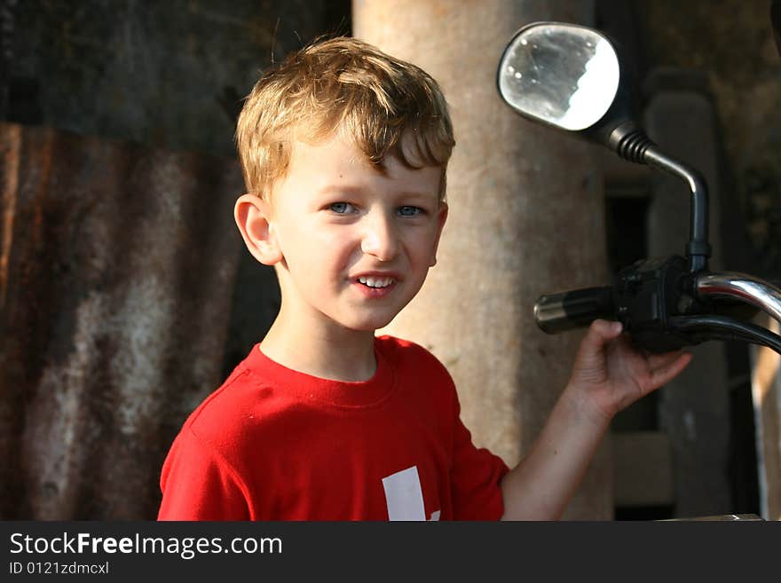 Young boy holding onto the handle of a motorbike. Young boy holding onto the handle of a motorbike