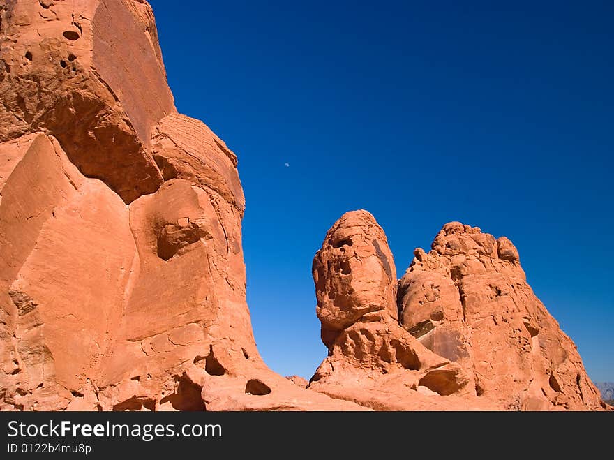 Red rock with moon under blue sky