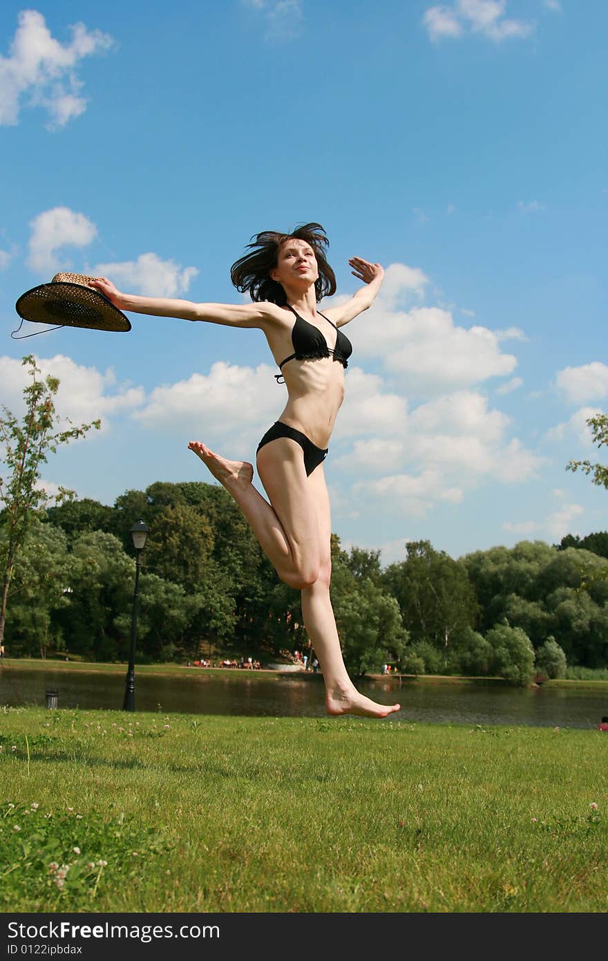 The girl jumps above the ground in a sunny day