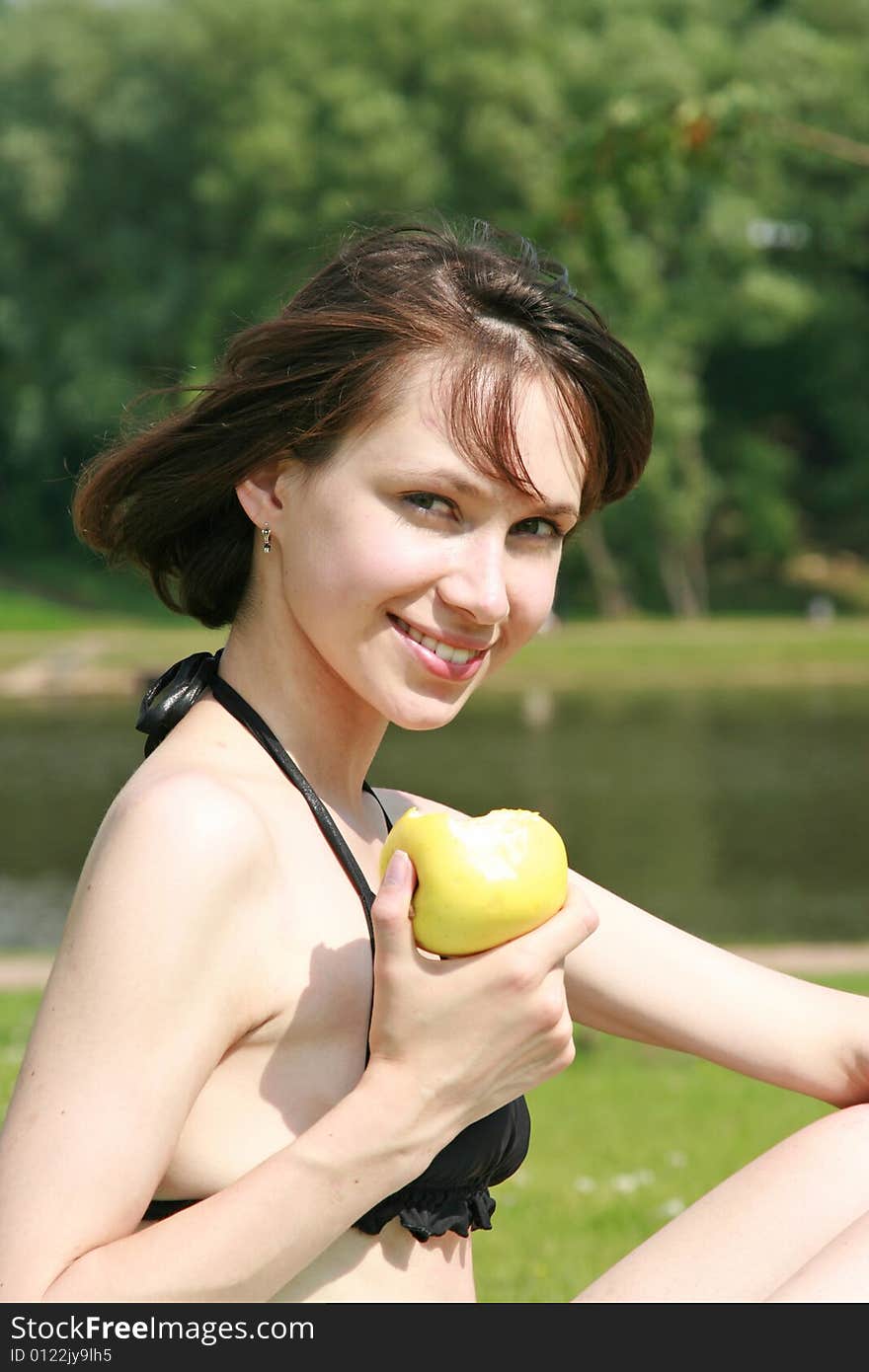 The beautiful girl in bikini eats an apple. The beautiful girl in bikini eats an apple