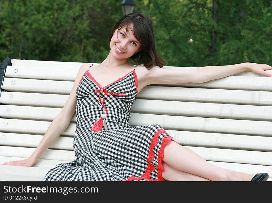 The beautiful girl poses on a bench. The beautiful girl poses on a bench