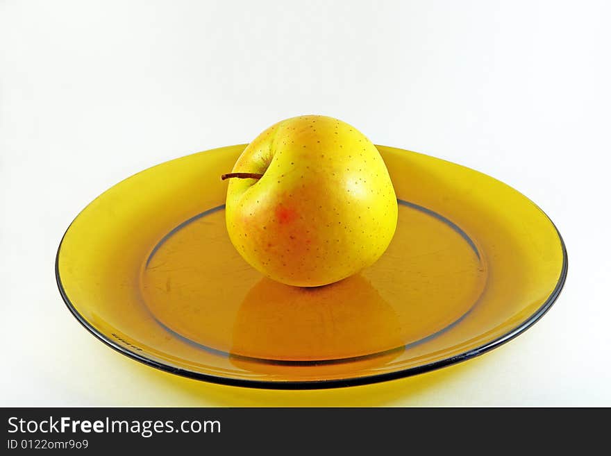 The yellow apple on the yellow dish