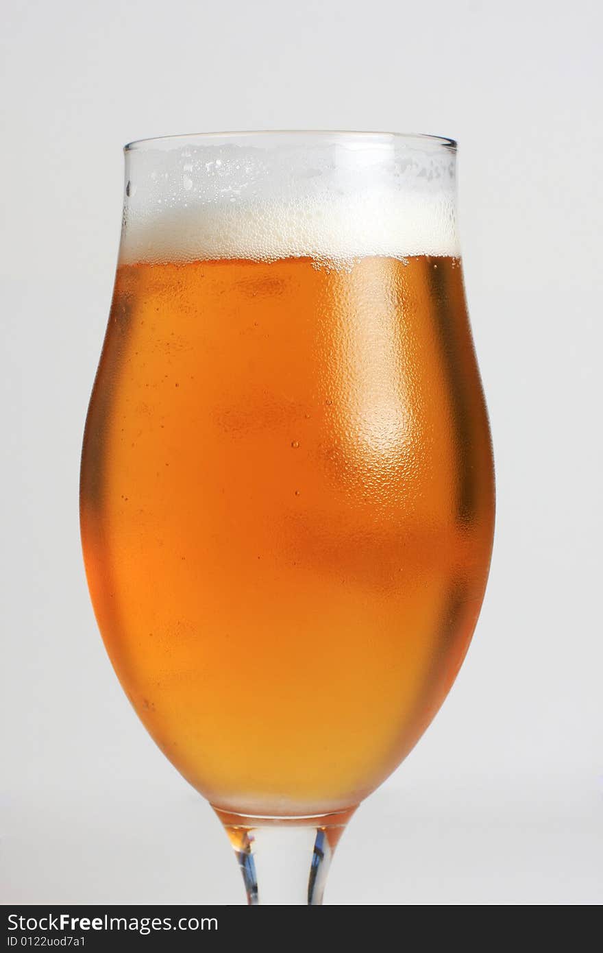 A glass of icecold beer, with condensing water on the glass.