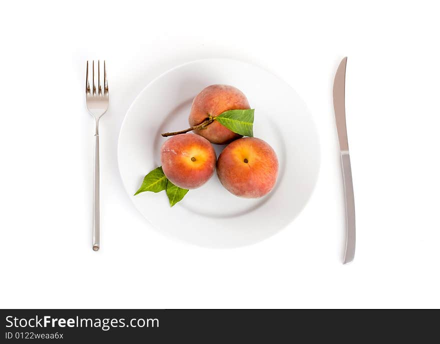 Peaches on a plate with fork and knife on the side