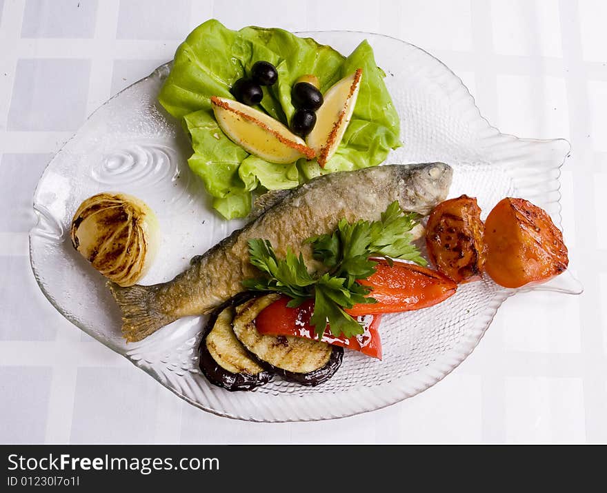 Fried fish with vegetables, salad and lemon