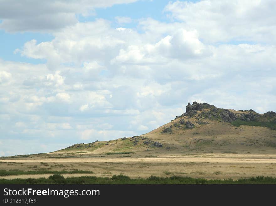 Steppe landscape. hill covered dry grass. sky with clouds