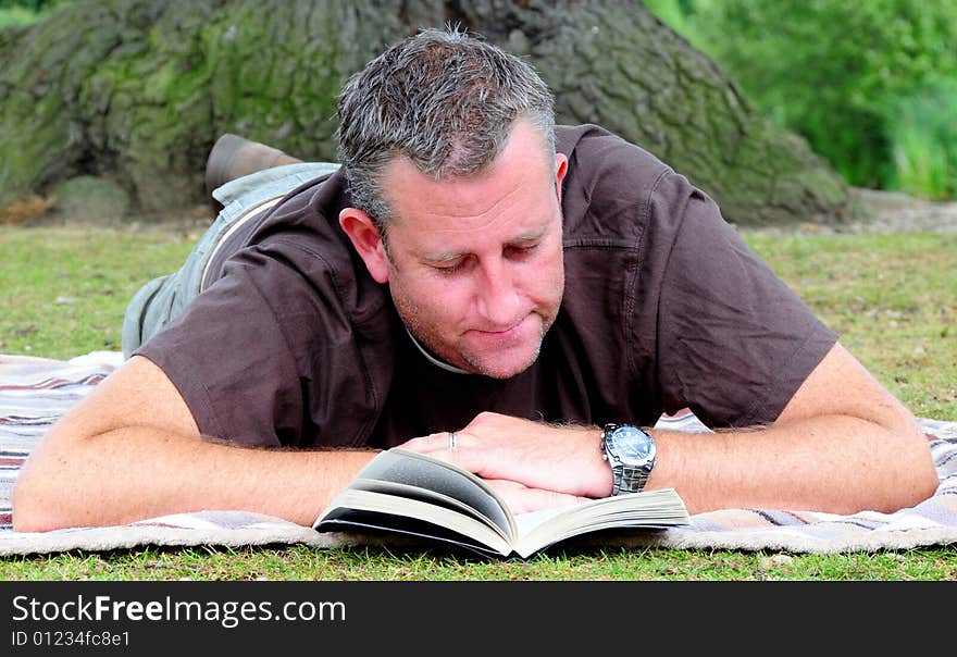 Shot of a man reading his book in the park