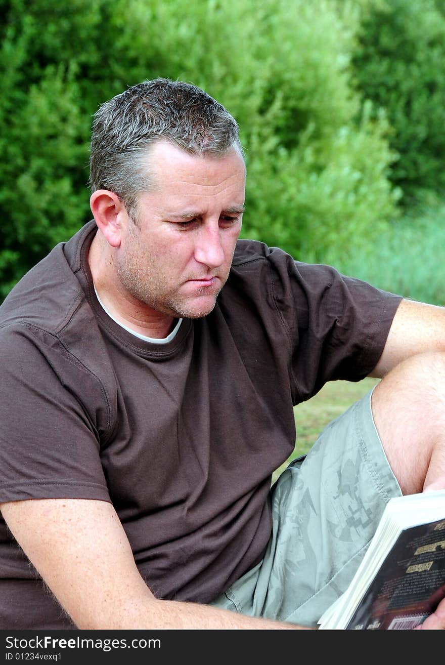 Shot of a man reading his book in the park