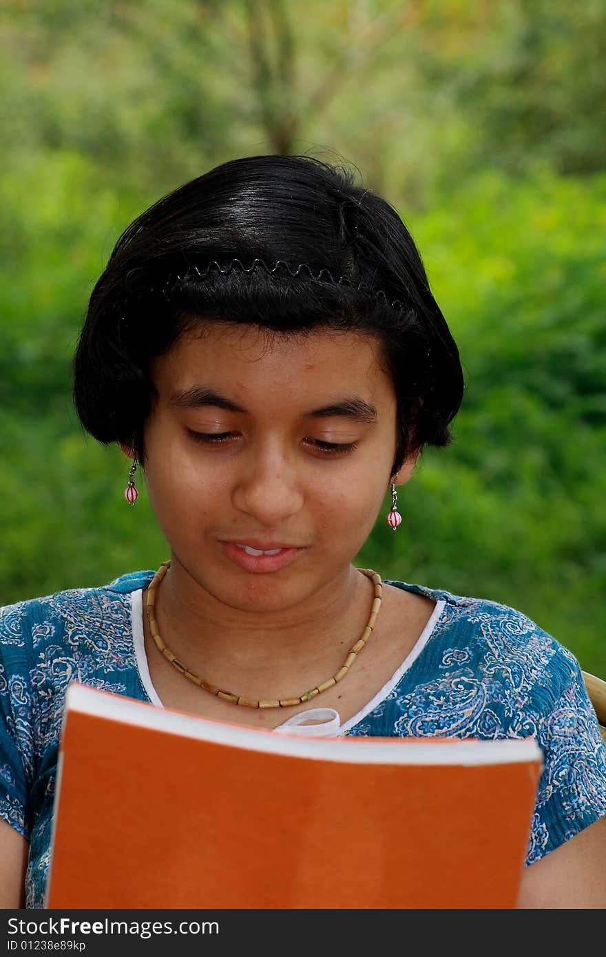 A girl getting absorbed in reading the magazine. A girl getting absorbed in reading the magazine.