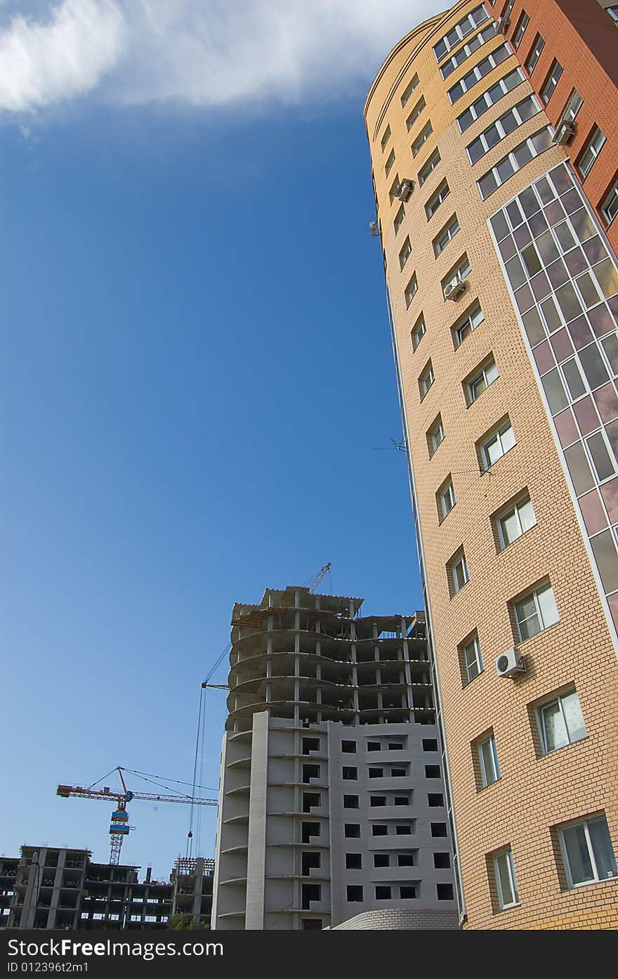 New brick multistory house in the foreground, construction works and tower crane in the background. New brick multistory house in the foreground, construction works and tower crane in the background