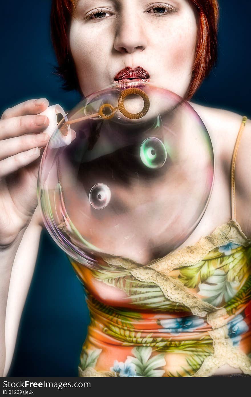 Red haired girl is trying to blow some big bubbles