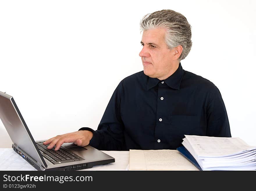 A businessman at work in his office writing a report with a laptop