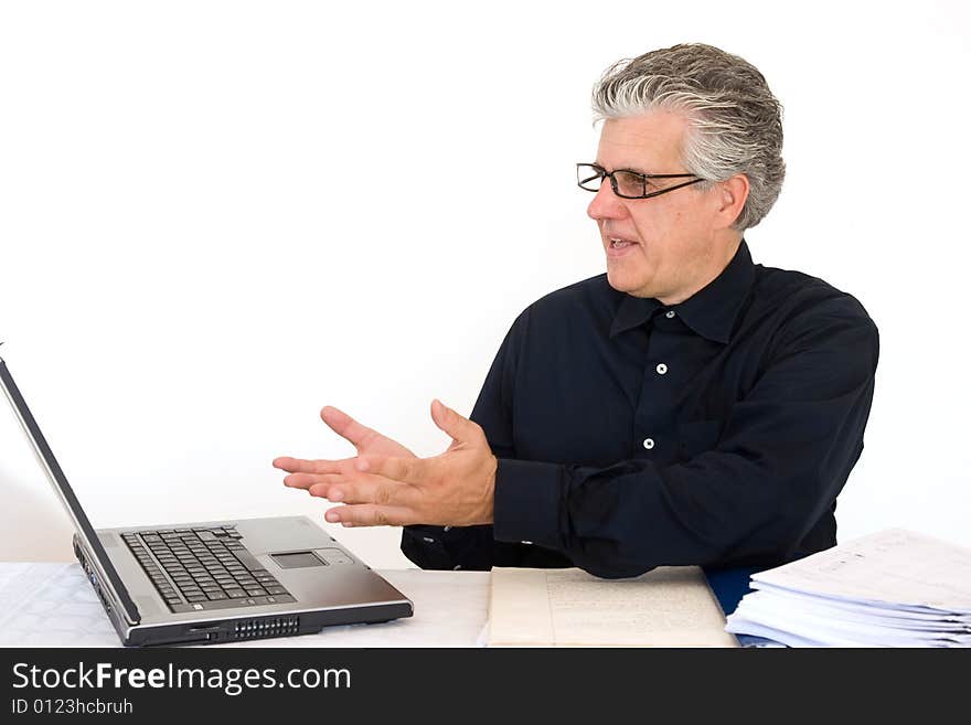 A businessman at work in his office writing a report with a laptop