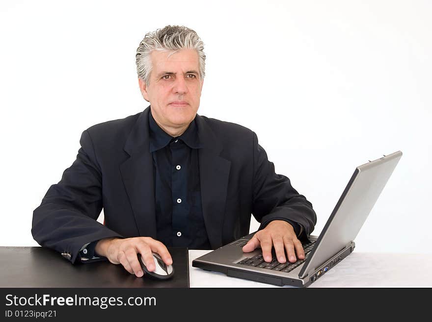 A businessman at work in his office writing a report with a laptop