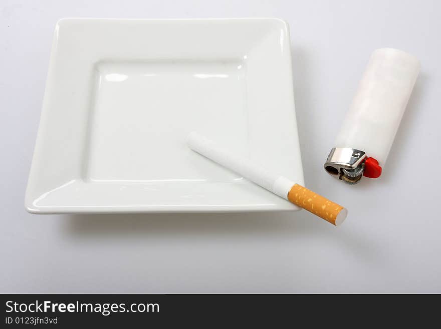 Unlit cigarette on white ashtray isolated on white white lighter to the side