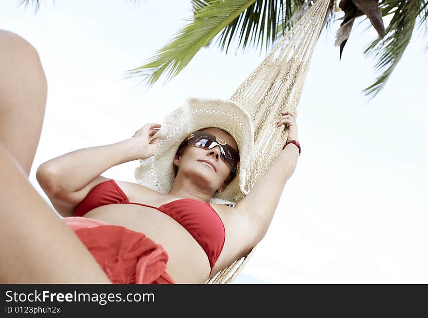 View of nice woman lounging in hammock in tropical environment