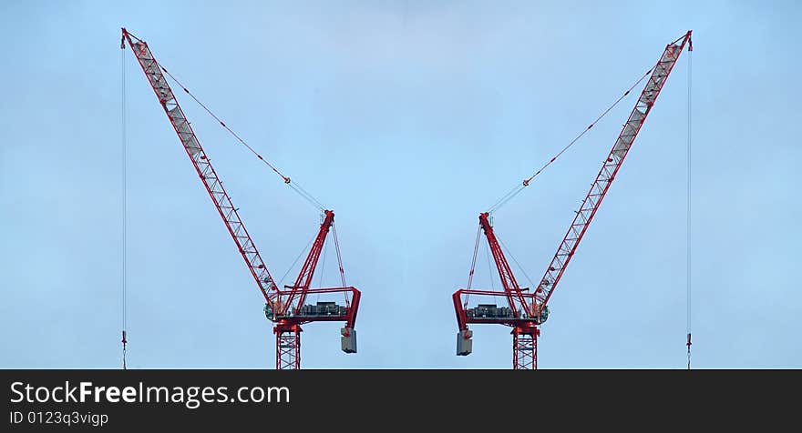 Construction cranes against sky background