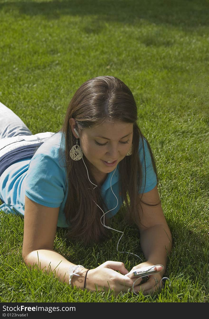 Girl relaxing in grass listening to music. Girl relaxing in grass listening to music