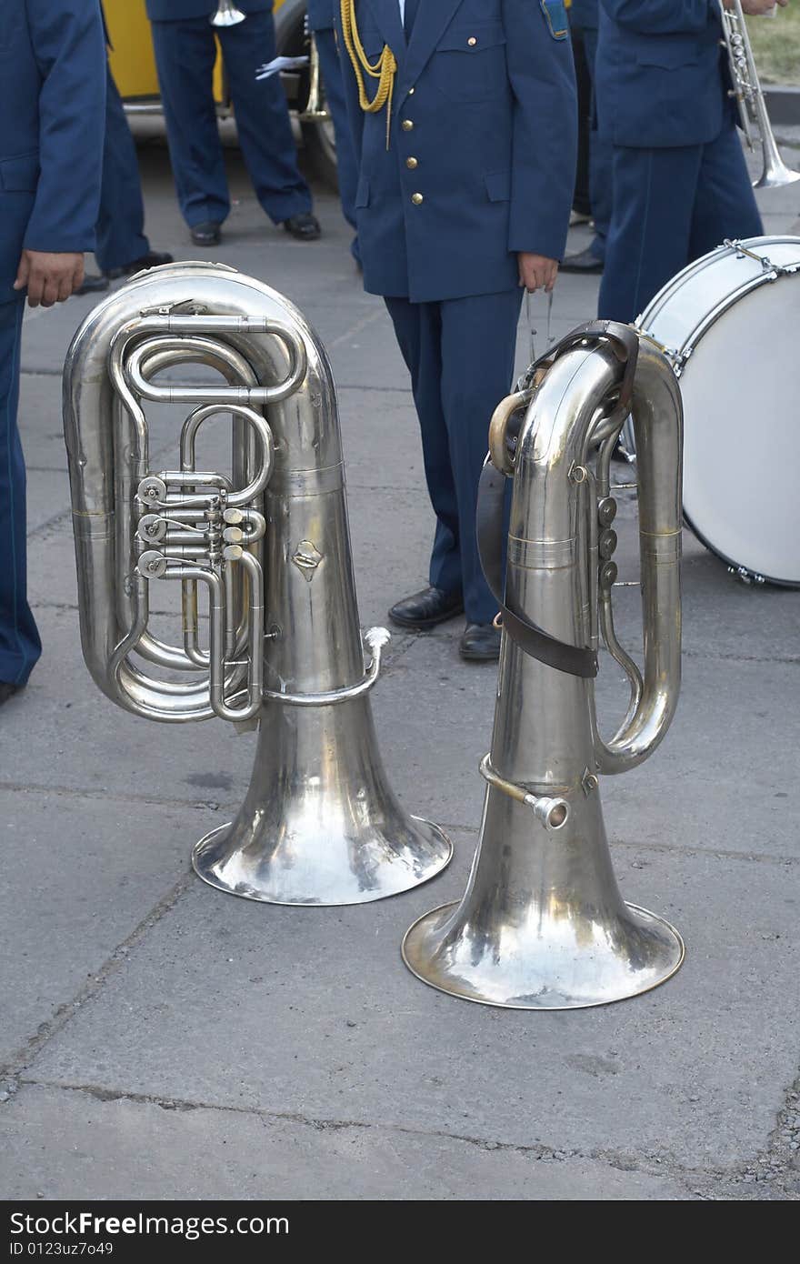 Two tubas and musicians from a military orchestra behind. Two tubas and musicians from a military orchestra behind