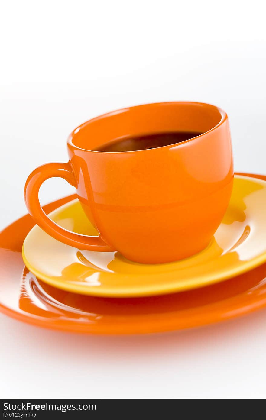 Orange coffee cup with yellow plate over white background