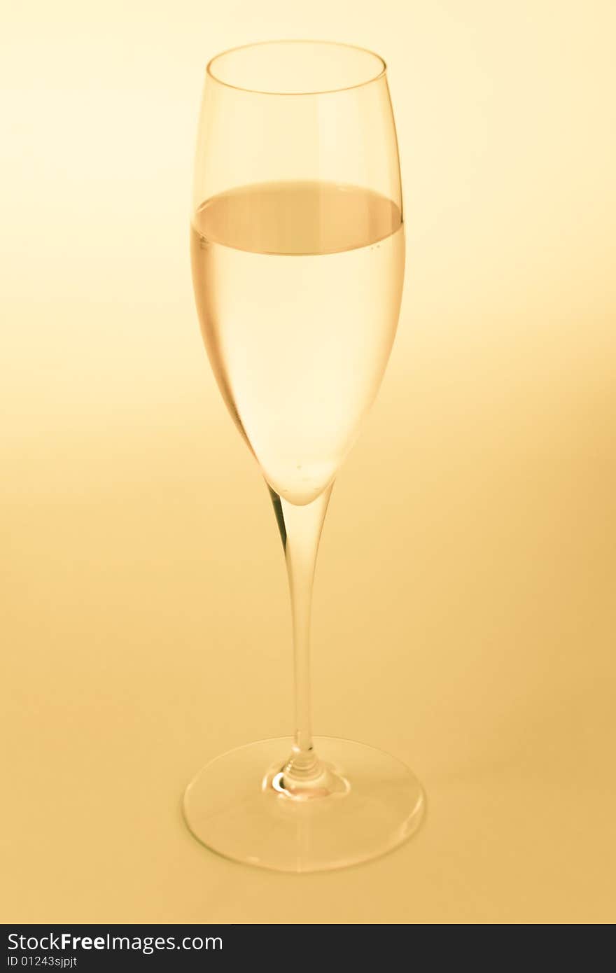 Golden sparkling wine glass over a yellow background. Golden sparkling wine glass over a yellow background